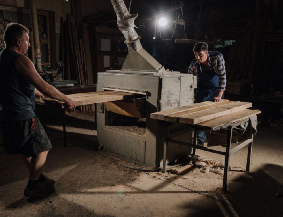 Photo montrant deux ouvriers en atelier en train de couper du bois